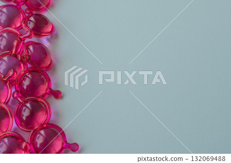 Bright pink hair capsules border on the left side of a clean light background, copy space 132069488