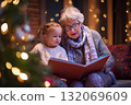 Christmas lights glow as a grandmother reads a storybook to her granddaughter. 132069609