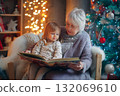 Christmas story time shared between grandmother and child beside tree. 132069610