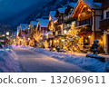 A snowy street lined with festive Christmas trees and illuminated houses lights up the winter night. 132069611