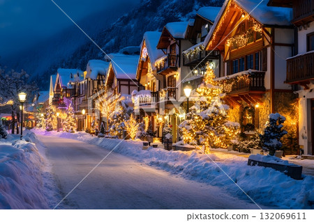 A snowy street lined with festive Christmas trees and illuminated houses lights up the winter night. 132069611