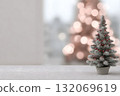 A small Christmas tree with red berries sits on a white surface. 132069619