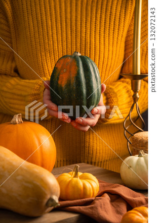 Orange, green and white squashes, female hands holding pumpkin, rustic moody background, autumn concept 132072143