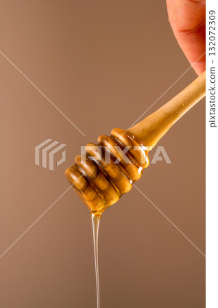 Close-up honey wooden dipper, sweet liquid, neutral background 132072309