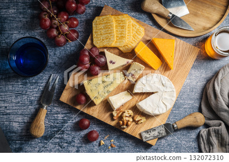 Cheese board, different types of cheese on a board, served with grapes and dried fruits. 132072310
