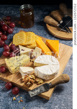 Cheese board, different types of cheese on a board, served with grapes and dried fruits. 132072312