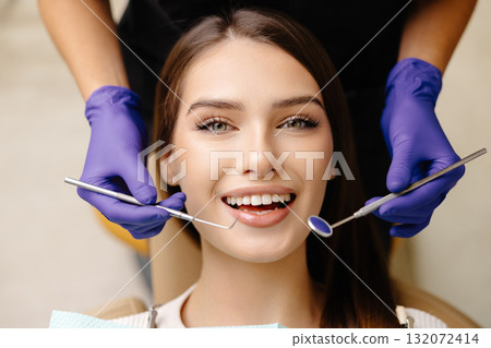 Happy patient during a visit to the dentist. The doctor is checking teeth using a dental instrument, ensuring proper oral care in the dentistry clinic 132072414