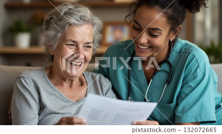 Caregiver shares joyful moment with senior woman while reviewing documents in a cozy living room 132072665