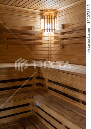Empty wooden sauna interior with tiered benches and warm light Empty wooden sauna interior with tiered benches and warm light 132072845