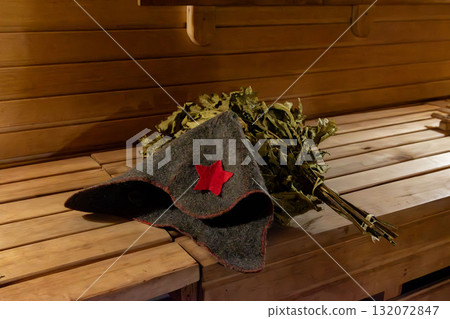 Soviet-style hat and bath broom in a rustic sauna 132072847