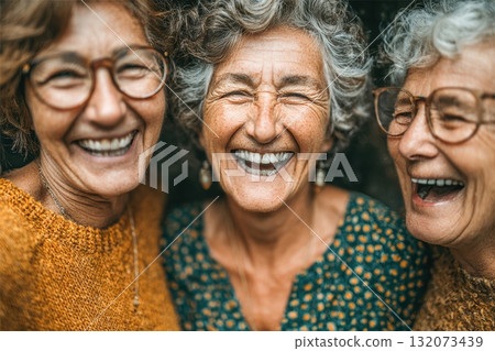 Three joyful elderly women laughing together in cozy knit sweaters 132073439