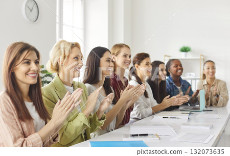 Group of multiracial women clapping hands and smiling while attending corporate seminar or training. 132073635