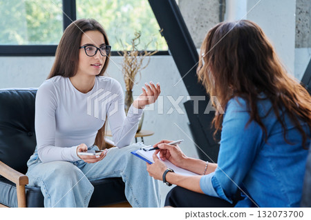Young smiling girl patient in therapy session with social mental therapist Young smiling girl patient in therapy session with social mental therapist 132073700