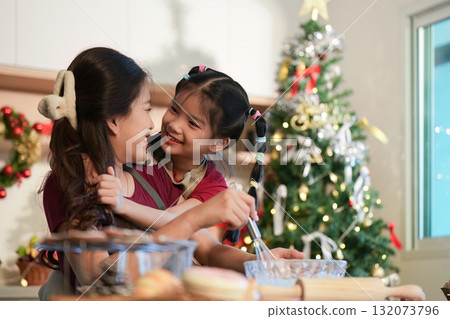 Joyful Baking. Mother and daughter sharing a fun moment while preparing holiday treats. 132073796