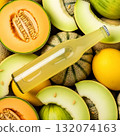 Melons and citrus fruits surrounding a bottle of refreshing beverage in a vibrant display 132074163
