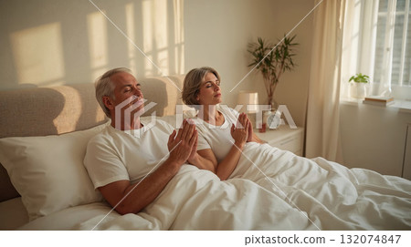 Elderly couple praying together in bed before sleep, surrounded by soft lighting and cozy bedding, reflecting a peaceful and spiritual moment Elderly couple praying together in bed before sleep, surrounded by soft lighting and cozy bedding, reflecting a peaceful and spiritual moment 132074847