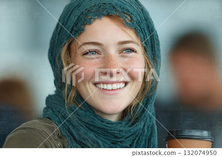 Smiling woman with scarf holding coffee cup in casual indoor setting 132074950