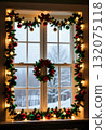 Decorations of green garlands and colorful ornaments surround a window, illuminated with warm lights, offering a festive view of a snowy landscape outside Generative AI 132075118