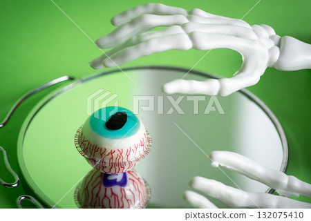 A skeleton hand reaching for a vivid glass eye with intricate blood vessels A skeleton hand reaching for a vivid glass eye with intricate blood vessels 132075410
