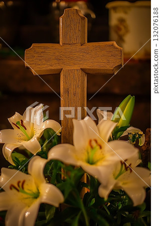 Wooden cross is placed on top of a bouquet of white lilies 132076188