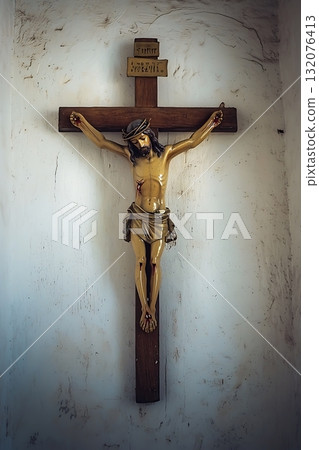 Wooden cross with a man on it, Jesus Christ, is hanging on a wall 132076413