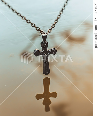 Silver cross necklace is reflected in the water 132076507