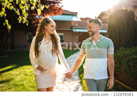 Expecting parents stroll together in evening sunlight 132076561