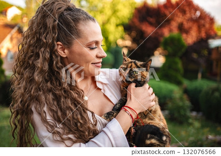 Woman enjoys a sunny afternoon with her adorable cat 132076566