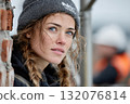 Young woman with braided hair wearing beanie, gazing thoughtfully outdoors 132076814