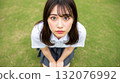 一名身穿制服的女高中生跪在草地上，直視著我。 132076992