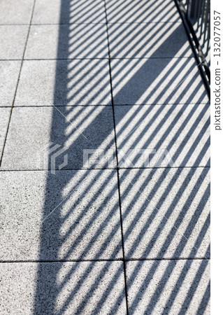 Striped shadow of a fence falling on tiles_Vertical 132077057