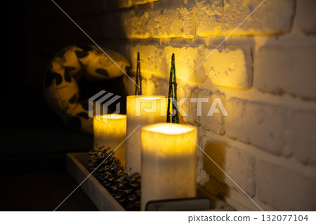 Cozy interior with glowing candles and soft warm light on brick wall. Peaceful home atmosphere and evening relaxation concept Cozy interior with glowing candles and soft warm light on brick wall. Peaceful home atmosphere and evening relaxation concept 132077104