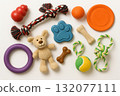 Collection of colorful dog toys including rubber ball, rope, frisbee, plush bear, and chew bones arranged on white background with copy space 132077111
