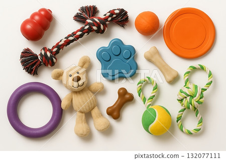 Collection of colorful dog toys including rubber ball, rope, frisbee, plush bear, and chew bones arranged on white background with copy space 132077111
