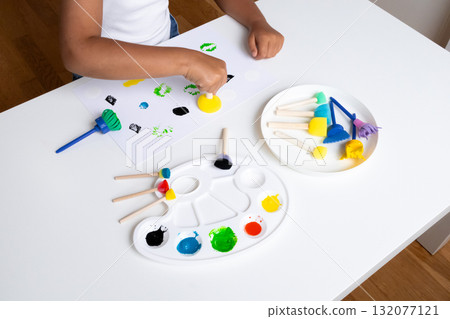 Child painting with colorful sponge stamps at home art table Child painting with colorful sponge stamps at home art table 132077121
