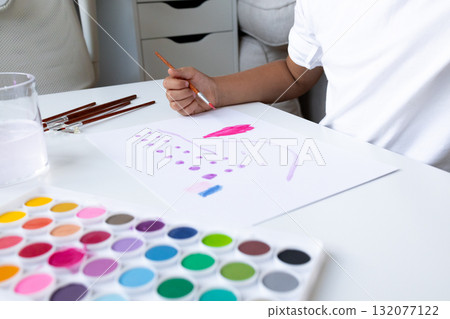 Child painting with watercolors at white table in bright room Child painting with watercolors at white table in bright room 132077122