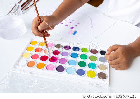 Child painting with colorful watercolors on white paper Child painting with colorful watercolors on white paper 132077125
