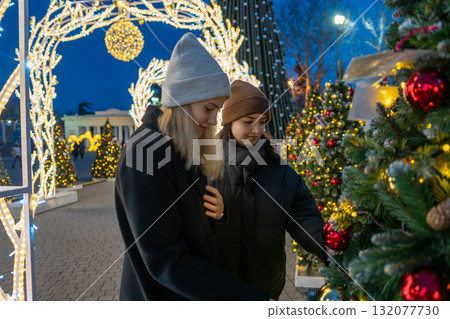 Young women Christmas holiday lights enjoying the winter festive market decorations together at night 132077730