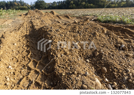 tracks in the sand on a part of the road in a field, road in a field with traces of heavy agricultural or construction vehicles tracks in the sand on a part of the road in a field, road in a field with traces of heavy agricultural or construction vehicles 132077843