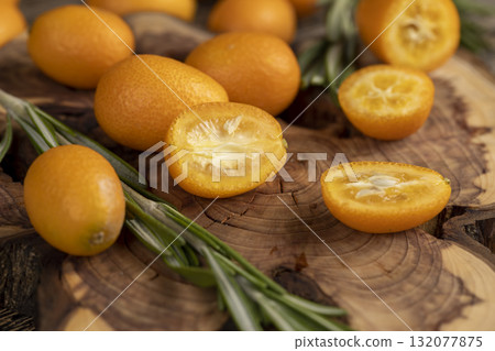 fresh sweet kumquat cut into halves on a wooden table, cut kumquat fruits lie on the table during cooking 132077875