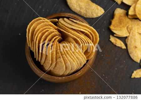 potato chips fried in oil and sprinkled with dried red sweet pepper, a large number of delicious salty chips with aromatic spices potato chips fried in oil and sprinkled with dried red sweet pepper, a large number of delicious salty chips with aromatic spices 132077886
