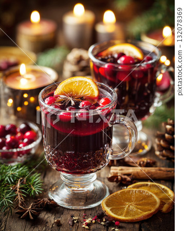 Two steaming glasses of traditional mulled wine or spiced punch, beautifully garnished with cranberries, orange slices, and star anise. Set on wooden table with pine branches, cinnamon sticks Two steaming glasses of traditional mulled wine or spiced punch, beautifully garnished with cranberries, orange slices, and star anise. Set on wooden table with pine branches, cinnamon sticks 132078369
