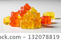 Close-up texture of orange and yellow multivitamin bears gummies in the form of bears on white background 132078819
