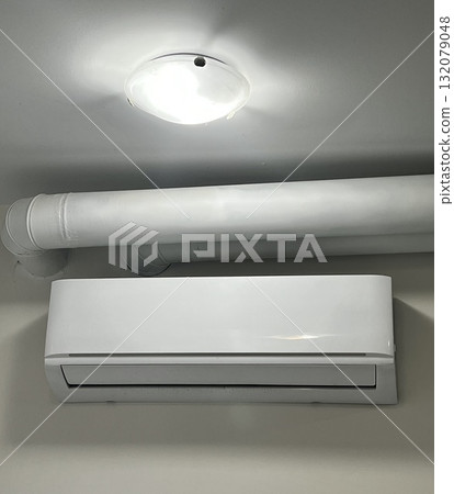 Air conditioning unit mounted on a wall in a bright room 132079048