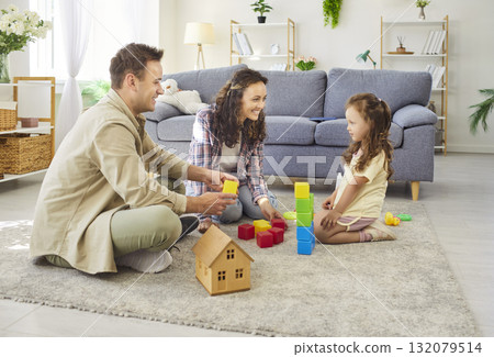 Smiling family playing with daughter building colorful blocks on carpet at home Smiling family playing with daughter building colorful blocks on carpet at home 132079514
