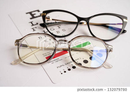 Glasses on eye exam chart to test eyesight accuracy of reading. Glasses on eye exam chart to test eyesight accuracy of reading. 132079780