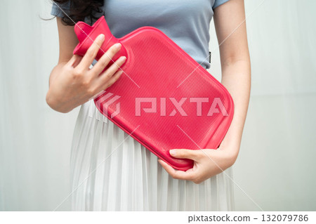 Woman using hot water bottle to relieve menstrual abdominal pain. Woman using hot water bottle to relieve menstrual abdominal pain. 132079786