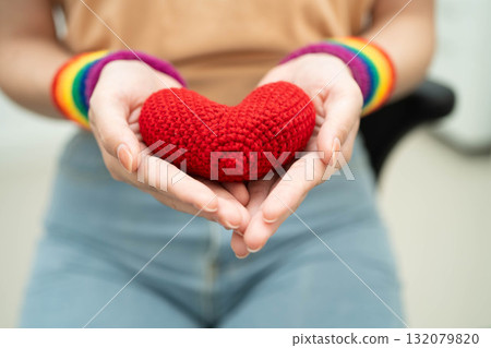 Asian woman holding LGBT heart with rainbow flag. Asian woman holding LGBT heart with rainbow flag. 132079820