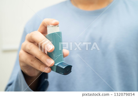Asthma and chronic obstructive pulmonary disease COPD, Asian young man using metered dose inhaler MDI. Asthma and chronic obstructive pulmonary disease COPD, Asian young man using metered dose inhaler MDI. 132079854