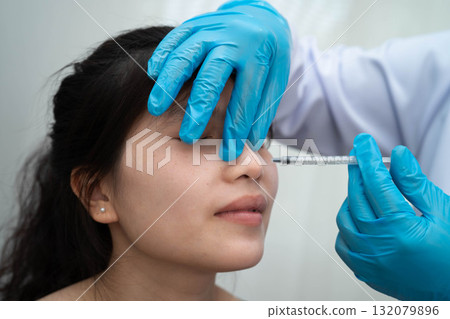Asian woman receiving plastic surgery shape of nose performed on face. Asian woman receiving plastic surgery shape of nose performed on face. 132079896